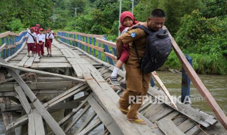 Seorang guru menggendong siswa SD Negeri 1 Alaaha saat menyeberangi jembatan rusak di Desa Alaaha, Kecamatan Ueesai, Kolaka Timur, Sulawesi Tenggara, Sabtu (21/1/2023). Jembatan yang menjadi akses satu-satunya dan penghubung tiga desa tersebut rusak akibat lapuk serta dorongan arus deras sungai Wandolaki sehingga menyebabkan sekitar 1.850 jiwa diwilayah tersebut tidak bisa beraktivitas normal. 