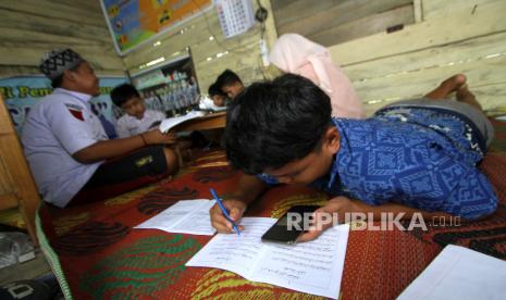 Sejumlah siswa mengikuti proses belajar mengajar dalam jaringan (daring) di bekas posko COVID-19 di tepi jalan untuk mendapatkan sinyal jaringan internet,  di Desa Madang, Kabupaten Hulu Sungai Selatan, Kalimantan Selatan, Selasa (4/8/2020). Siswa sekolah di pelosok Kalimantan Selatan masih kesulitan untuk mengikuti proses belajar mengajar daring selama masa pandemi COVID-19 akibat sulitnya akses internet di daerah itu. 