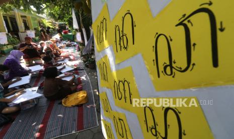 Sejumlah murid menulis aksara Jawa dengan bimbingan guru.