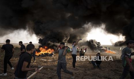 Warga Palestina membakar ban selama protes terhadap serangan militer Israel di Tepi Barat, di sepanjang pagar perbatasan dengan Israel, di timur Kota Gaza, Selasa, 25 Oktober 2022. Militer mengatakan pasukan Israel telah menyerbu sebuah kubu kelompok bersenjata di Tepi Barat, meledakkan laboratorium bahan peledak dan terlibat dalam baku tembak. Pejabat kesehatan Palestina mengatakan lima warga Palestina tewas dan 20 lainnya terluka. Sasaran serangan itu adalah kelompok yang menamakan dirinya Sarang Singa, yang dituduh oleh Israel telah membunuh seorang tentara dan mencoba beberapa serangan.