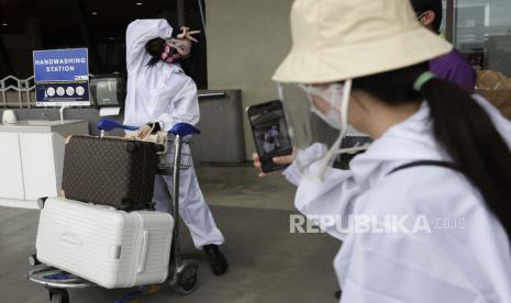  Penumpang asing yang mengenakan pakaian pelindung memeriksa barang-barang mereka saat mereka bersiap untuk penerbangan mereka ke China di Bandara Internasional Manila, Filipina, Senin, 18 Januari 2021. 