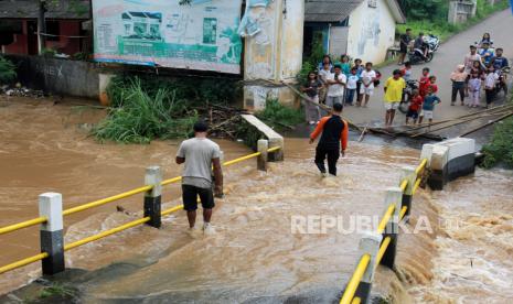 Warga melintasi banjir yang merendam jembatan di perumahan Villa Pamulang, Pamulang, Tangerang Selatan, Rabu (18/3/2020). Banjir setinggi 50cm - 1meter ini disebabkan meluapnya kali Angke akibat kiriman air dari Bogor yang dilanda hujan deras. 