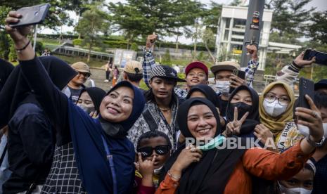 Warga berswafoto dengan Remaja asal Citayam yang viral, Bonge (tengah) di kawasan Dukuh Atas, Jakarta, Rabu (6/7/2022). Area sekitar taman Stasiun MRT Dukuh Atas menjadi ruang publik favorit yang ramai didatangi oleh kalangan remaja dari daerah pinggiran Ibu Kota. Kedatangan mereka untuk menghabiskan waktu libur sekolah dengan bercengkrama bersama sahabat dan membuat konten media sosial. Republika/Putra M. Akbar