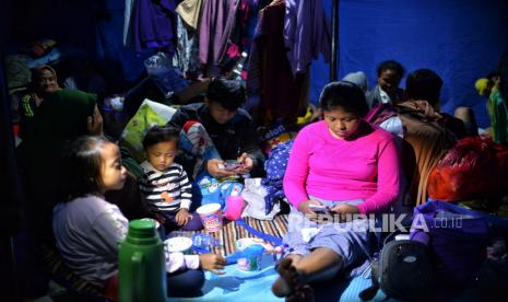 Pengungsi beraktivitas di dalam tenda darurat di Kampung Gitung, Desa Mangunkerta, Kecamatan Cugenang, Kabupaten Cianjur, Jawa Barat, Ahad (27/11/2022). Beberapa pengungsi korban gempa Cianjur mengisi waktu malam hari di tenda pengungsian dengan menggelar tahlil atau menyaksikan pertandingan piala dunia. Republika/Thoudy Badai