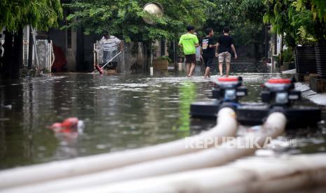 Sejumlah warga melintasi genangan banjir di Perumahan Jatibening Permai, Bekasi, Jawa Barat, Ahad (24/1). Banjir terjadi akibat hujan deras yang mengguyur sejak pagi mengakibatkan Kali Cakung meluap hingga menggenangi permukiman tersebut setinggi 1 meter. Prayogi/Republika.