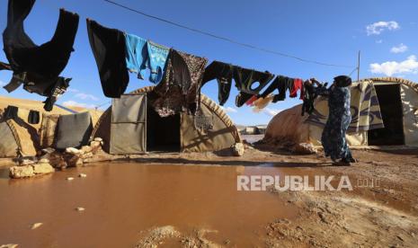 Seorang wanita menggantung cucian di kamp pengungsi yang terendam banjir di provinsi Idlib, Suriah, Selasa, 21 Desember 2021.