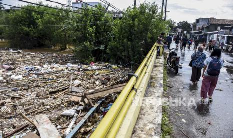 Sejumlah warga melintas di samping Sungai Cikapundung Baru yang ditutupi oleh sampah di Dayeuhkolot, Kabupaten Bandung, Rabu (1/4). Berdasarkan keterangan warga, sudah tiga hari sampah tersebut mengendap di Sungai Cikapundung Baru dan berharap kepada dinas terkait untuk segera melakukan penanganan atau pengerukan di area tersebut guna meminimalisir risiko terjadinya banjir di kawasan tersebut