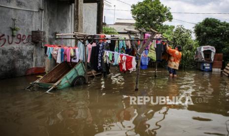 Seorang warga menjemur pakaian di tengah banjir di kawasan Benda, Kota Tangerang, Banten, Rabu (19/1/2022). Banjir tersebut terjadi karena buruknya drainase di kawasan itu serta tingginya instensitas hujan pada Selasa (18/1) siang. 