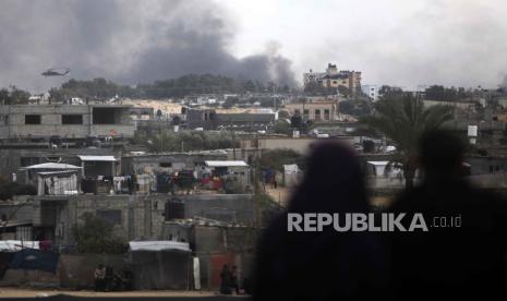 Warga Palestina menyaksikan helikopter Israel terbang di atas Khan Younis, Jalur Gaza, Kamis, (15/2/2024).