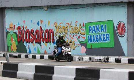 Pengendara motor melintas di dekat dinding bermural di terowongan Mayjen Sungkono, Surabaya, Jawa Timur, Minggu (22/11/2020). Mural di dinding terowongan tersebut merupakan sarana imbauan kepada warga untuk tetap menerapkan protokol kesehatan pencegahan penularan COVID-19. 