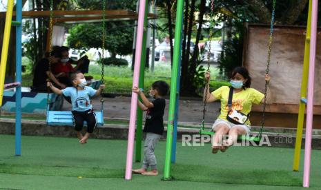 Seorang perempuan dan anak-anak menggunakan masker saat bermain ayunan di Taman Catur, Pontianak, Kalimantan Barat, Selasa (4/5/2021). Wali Kota Pontianak, Kalimantan Barat, Edi Rusdi Kamtono mengancam sanksi denda kepada pengunjung taman yang membuang sampah sembarangan di kota itu untuk memberikan efek jera.