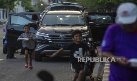 Seorang anak berlari setelah mendapatkan Hagala berbentuk makanan dari dermawan di salah satu ruas jalan di Palu, Sulawesi Tengah, Senin (11/4/2022). Hagala adalah sedekah yang bisa berbentuk sandang, pangan, papan, atau uang tunai oleh dermawan yang diberikan kepada keluarga kurang mampu dan menjadi tradisi pada setiap bulan Ramadhan.