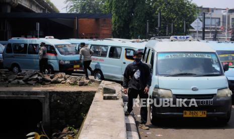 Warga berjalan di dekat angkot 44 jurusan Tebet-Tanah Abang yang sedang melakukan aksi mogok di Halte Integrasi Tebet, Jakarta, Rabu (10/5/2023). Pada aksinya mereka melakukan aksi mogok dan memarkirkan kendaraan hingga menutup akses armada Jaklingko untuk melintas. Mereka menuntut pengurangan armada bus Jaklingko pada rute yang serupa karena mengurangi pendapatan sopir angkot.