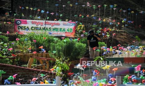 Warga melintas diantara hiasan kincir angin di Desa Wisata Lahan Hutan Raya Mulung Layung di Babakan Cipanas, Kabupaten Sumedang, Jawa Barat, Sabtu (25/7/2020). Warga Desa Cipanas berinisiatif untuk merubah lahan hutan yang tidak terpakai untuk dijadikan tempat wisata secara swadaya guna mendongkrak perekonomian warga di Desa. ANTARA FOTO/Raisan Al Farisi/hp.