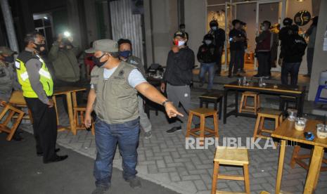 Petugas gabungan dari TNI, Polri dan Satpol PP melakukan razia jam malam di kafe kopi daerah Bekasi, Jawa Barat, Sabtu (3/10/2020). Pemerintah setempat mengeluarkan aturan pembatasan waktu operasional tempat makan, pertokoan dan tempat hiburan hingga pukul 18.00 WIB untuk mencegah peningkatan kasus COVID-19. 