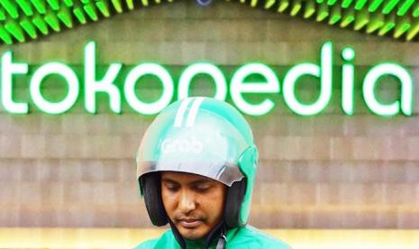 Seorang pengemudi Gojek berdiri di depan banner Tokopedia (Foto istimewa).