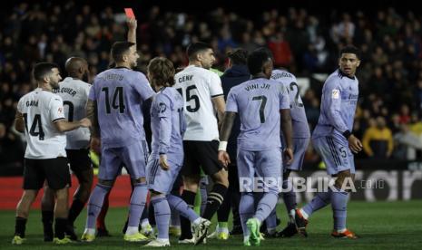 Wasit Gil Manzano memberikan kartu merah kepada Jude Bellingham (kanan), pencetak gol yang dianulir di akhir pertandingan setelah pertandingan sepak bola LaLiga antara Valencia CF dan Real Madrid, di Valencia, Spanyol, Ahad (2/3/2024) dini hari.