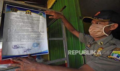 Anggota Satpol PP memasang surat pernyataan bersama larangan berjualan bagi rumah makan di siang hari saat razia penegakkan Perda Bulan Ramadhan di Serang, Banten, Senin (11/5/2020). Pemkot Serang mengeluarkan Perda larangan berjualan bagi restoran dan warung makan di siang hari yang dikuatkan oleh MUI serta Kementerian Agama selama bulan Ramadhan untuk menghormati orang berpuasa