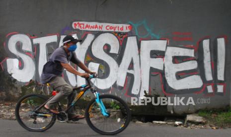 Pengendara sepeda melintas di depan mural sosialisasi COVID-19 saat Pembatasan Sosial Berskala Besar (PSBB) di jalan Sudimoro, Malang, Jawa Timur, Kamis (28/5/2020). Forum Koordinasi Pimpinan Daerah (Forkopimda) Jatim dan Malang Raya memutuskan untuk tidak akan memperpanjang PSBB di kawasan Malang Raya (Kabupaten Malang, Kota Malang dan Kota Batu) yang berakhir pada tanggal 30 Mei 2020 serta berencana akan melanjutkan dengan Masa Transisi Normal Baru