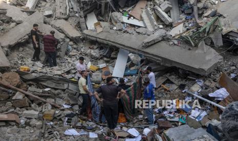 Orang-orang berdiri di antara puing-puing Gereja Ortodoks Saint Porphyrius menyusul serangan udara di Gaza, 20 Oktober 2023.