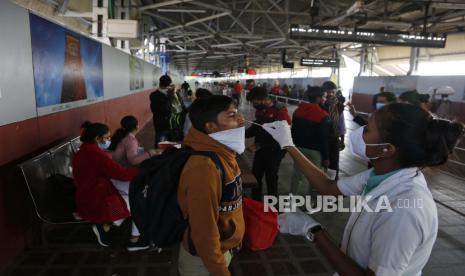  Seorang petugas kesehatan mengambil sampel swab penumpang yang memasuki kota untuk tes COVID-19 di stasiun kereta api di Ahmedabad, India, Jumat, 3 Desember 2021. India pada Kamis mengkonfirmasi kasus pertama varian virus corona omicron di dua orang dan pejabat mengatakan satu tiba dari Afrika Selatan dan yang lainnya tidak memiliki riwayat perjalanan. Seorang ahli medis terkemuka mendesak orang untuk divaksinasi.