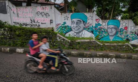 Warga tidak bermasker melintas di depan mural dukungan tenaga medis di Rangkasbitung, Lebak, Banten, Rabu (30/6/2021). Berdasarkan data Pemprov Banten, Kabupaten Lebak menjadi salah satu dari empat daerah selain Tangerang Selatan, Tangerang Kota, dan Kabupaten Tangerang  yang berstatus zona merah COVID-19 di Banten. Kasus Covid-19 Naik, Pemkab Tangerang Ingatkan Warga Pakai Masker