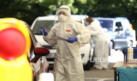 Petugas kesehatan mengumpulkan sampel di stasiun pengujian COVID-19 sementara di Mamming, Jerman, Selasa, 28 Juli 2020. Jerman berencana memperpanjang pembatasan demi mencegah penyebaran Covid-19 hingga 14 Maret 2021.