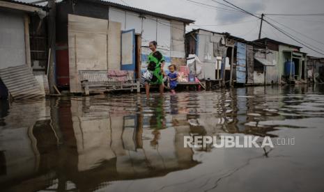 Warga berjalan di kawasan yang terkena banjir rob di Dadap, Kabupaten Tangerang, Banten, Jumat (12/11/2021). Banjir rob yang melanda kawasan tersebut sejak Kamis (4/11/2021) mulai berangsur surut. 