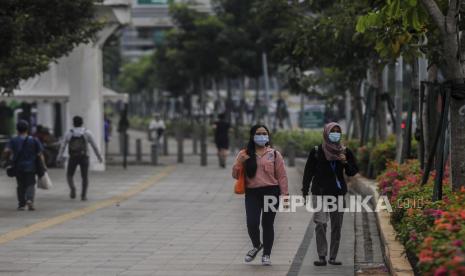 Warga menggunakan masker saat melintasi kawasan Sudirman, Jakarta,Ahad (11/10). Pemerintah Provinsi DKI Jakarta mengurangi kebijakan rem darurat di Ibu Kota dengan kembali memberlakukan Pembatasan Sosial Berskala Besar (PSBB) Transisi mulai Senin (12/10) hingga Senin (25/10), karena adanya pelambatan kenaikan kasus positif dan kasus aktif Covid-19 meski masih terjadi peningkatan penularan. Republika/Putra M. Akbar