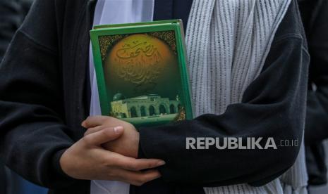 Pelajar Palestina memegang kitab suci Alquran saat berunjuk rasa mengecam aksi pembakaran Alquran oleh politisi sayap kanan Swedia Rasmus Paludan, di Gaza, Selasa (24/2/2023) waktu setempat.