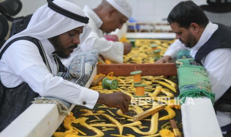 Pekerja Saudi menyulam kaligrafi Islam, baik menggunakan benang perak murni atau benang perak berlapis emas, selama tahap akhir persiapan tirai, atau Kiswah, yang menutupi Kabah, struktur berbentuk kubus di jantung Masjidil Haram, di pabrik Kiswah di Mekkah, Arab Saudi, Rabu, 6 Juli 2022. Jemaah haji berkumpul di kota suci Mekah di Arab Saudi untuk haji terbesar sejak pandemi virus corona sangat membatasi akses ke salah satu dari lima rukun Islam,