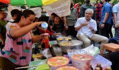 Capres nomor urut 3 Ganjar Pranowo menyantap jajanan jagung susu keju pedagang kaki lima (PKL) bersama warga saat mengunjungi Obyek Mata Air Cokro (OMAC) di Juragan Jero, Daleman, Kecamatan Tulung, Kabupaten Klaten, Jawa Tengah, Rabu (27/12/2023). Pada kesempatannya, Ganjar menyapa warga yang sedang berwisata di Umbul Cokro atau Obyek Mata Air Cokro setelah menemui petani tembakau di Gudang Tembakau Empatlima Pager, Klaten.