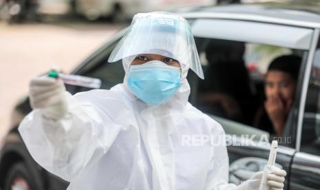  Petugas kesehatan dengan jas hazmat mengumpulkan sampel spesimen selama drive melalui uji coba swab COVID-19 di Medan, Sumatera Utara, Indonesia, 15 Desember 2020. 