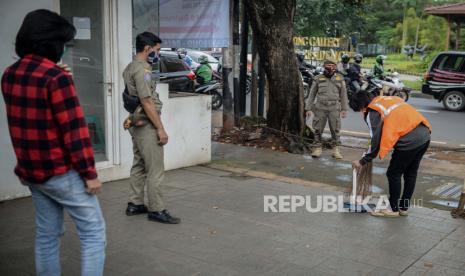 Warga dikenai sanksi sosial saat razia masker dengan membersihkan Jalan Ampera Raya di Jakarta, Selasa (2/1). Perlunya kesadaran masyarakat untuk menerapkan protokol kesehatan salah satunya menggunakan masker saat beraktivitas untuk menekan angka positif Covid-19 yang kian bertambah di tengah Pemberlakuan Pembatasan Kegiatan Masyarakat (PPKM) hingga 8 Februari mendatang. Republika/Thoudy Badai