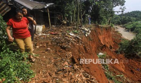 Sejumlah warga melintas di pinggir jalan yang longsor di Kawasan Pasir Putih, Depok, Jawa Barat, Senin (8/11/2021). Hujan lebat yang mengguyur wilayah Pasir Putih Depok pada Minggu (7/11) tersebut menyebabkan terjadinya longsor yang mengancam permukiman warga di kawasan itu. 