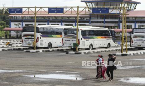 Sejumlah penumpang melintasi area parkir bus di Terminal Jatijajar, Depok, Jawa Barat, Kamis (28/1/2021). Badan Pengelola Transportasi Jabodetabek (BPTJ) mencatat selama Pemberlakuan Pembatasan Kegiatan Masyarakat (PPKM) jumlah penumpang Angkutan Antar Kota Antar Provinsi (AKAP) di Terminal Jatijajar menurun hingga 29,2 persen, yaitu dari sebanyak 311 penumpang per hari menjadi 220 penumpang per hari. 