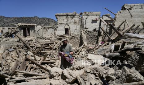  Seorang pria Afghanistan menggendong anaknya di tengah kehancuran setelah gempa bumi di desa Gayan, di provinsi Paktika, Afghanistan, Jumat, 24 Juni 2022. Gempa kuat melanda wilayah pegunungan berbatu di Afghanistan timur Rabu pagi, meratakan rumah-rumah batu dan bata lumpur di gempa paling mematikan di negara itu dalam dua dekade, kantor berita pemerintah melaporkan.