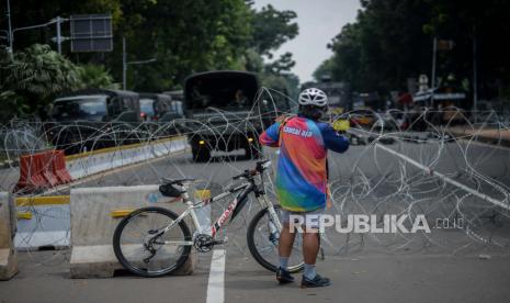 Warga bersepeda di Jalan Medan Merdeka Barat, Jakarta, Selasa (20/20). Sebanyak 1.200 personel gabungan dari aparat kepolisian dan anggota TNI dikerahkan untuk mengamankan demonstrasi yang digelar BEM SI terkait penolakan terhadap UU Omnibus Law Cipta Kerja sekaligus peringatan satu tahun pemerintahan Joko Widodo dan Maruf Amin di kawasan Istana Negara. Republika/Thoudy Badai