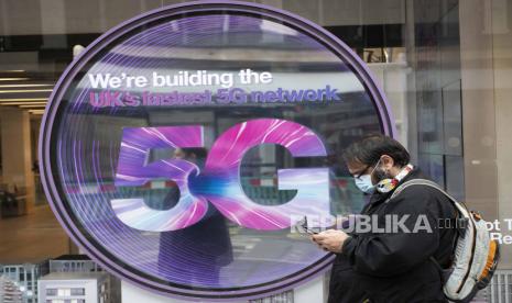  Seorang anggota masyarakat memeriksa teleponnya di luar sebuah toko ponsel yang menampilkan tanda 5G, Oxford Street, London. Jumat 12 Juni 2020.