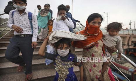  Pekerja migran menyeberangi jembatan penyeberangan menuju terminal bus saat mereka berjalan untuk naik bus untuk desa masing-masing menyusul penguncian selama enam hari di New Delhi, India, Selasa, 20 April 2021. 