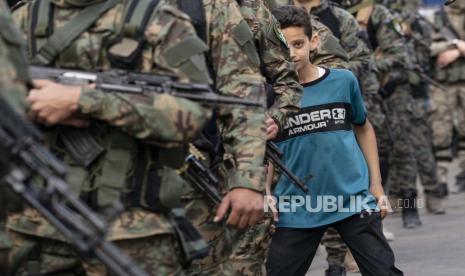 Seorang anak berkelok-kelok di antara barisan militan Hamas saat mereka berpawai di jalan-jalan untuk Bassem Issa, seorang komandan Hamas, yang terbunuh oleh tindakan militer Angkatan Pertahanan Israel sebelum gencatan senjata dicapai setelah perang 11 hari antara penguasa Hamas Gaza dan Israel, di Kota Gaza, Sabtu, 22 Mei 2021.