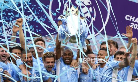 Pemain Manchester City Fernandinho (tengah) mengangkat trofi saat rekan satu timnya merayakannya setelah memenangkan gelar Liga Utama Inggris setelah pertandingan sepak bola Liga Utama Inggris antara Manchester City dan Aston Villa di Manchester, Inggris, Ahad (22/5/2022) malam WIB.