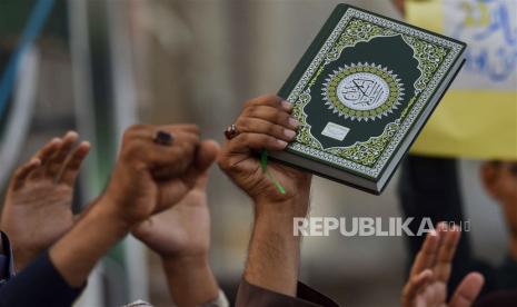  Demonstran mengangkat tangan dan mengangkat Alquran saat mereka menghadiri protes menentang pembakarannya di Swedia, di Karachi, Pakistan, Ahad (2/7/2023).