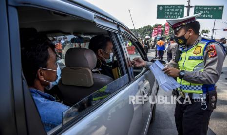 Petugas kepolisian memeriksa identitas pengemudi kendaraan dengan plat nomor dari luar Bandung di posko penyekatan larangan mudik di gerbang Tol Padalarang, Kabupaten Bandung Barat, Senin (10/5). Pada hari kelima penerapan larangan mudik Lebaran 2021, petugas gabungan di posko penyekatan larangan mudik Padalarang telah memutarbalikan sedikitnya 30 kendaraan berplat luar kota karena tidak memiliki surat kesehatan serta ijin perjalanan. Foto: Republika/Abdan Syakura