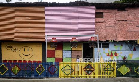 Anak-anak melintasi pemukiman penduduk yang dihias dengan mural di Jalan Hasbi, Kecamatan Tanah Abang, Jakarta Pusat, Senin (5/12/2022).