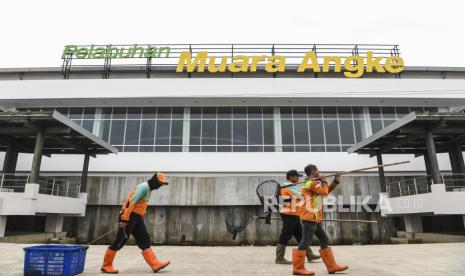 Petugas kebersihan melintas di depan gedung Pelabuhan Kali Adem Muara Angke, Jakarta.