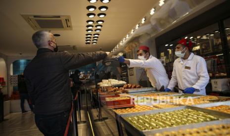 Turki Perketat Pembatasan Covid-19 Saat Ramadhan. Seorang pria membeli manisan tradisional Turki di sebuah restoran, di Istanbul, Selasa, 13 April 2021.