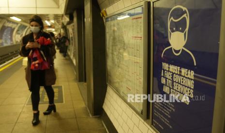  Seorang komuter berjalan melewati poster informasi TFL (Transport for London) yang memberi tahu penumpang bahwa wajib memakai masker di angkutan umum untuk menghentikan penyebaran COVID-19, di London, Selasa, 30 November 2021.