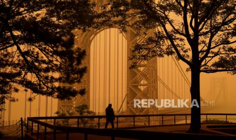 CORRECTS DATELINE TO FORT LEE, NOT ENGLEWOOD CLIFFS - A man talks on his phone as he looks through the haze at the George Washington Bridge in Fort Lee, N.J., Wednesday, June 7, 2023. Intense Canadian wildfires are blanketing the northeastern U.S. in a dystopian haze, turning the air acrid, the sky yellowish gray and prompting warnings for vulnerable populations to stay inside. 