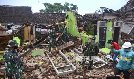 Tentara Indonesia membantu membersihkan puing-puing di sebuah rumah yang rusak akibat gempa bumi di Malang, Jawa Timur, Indonesia, Minggu, 11 April 2021. 